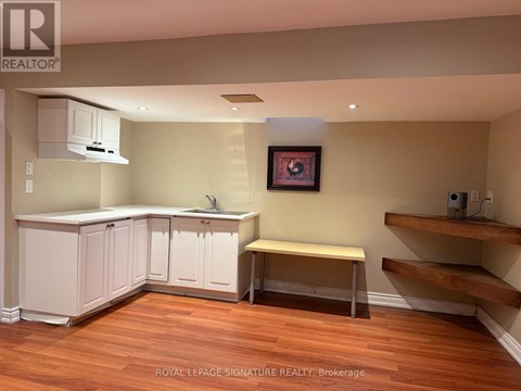 A kitchen with white cabinets and a wooden floor.