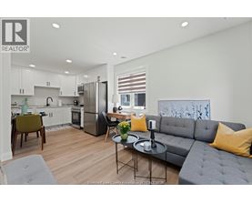 A modern kitchen with a grey couch and a dining table.
