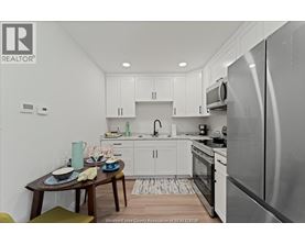 A kitchen with white cabinets and a wooden table set for two.