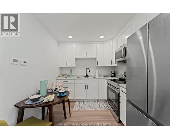 A kitchen with white cabinets and a wooden table set for two.