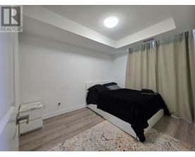 A bedroom with a bed, nightstand, and window with curtains.
