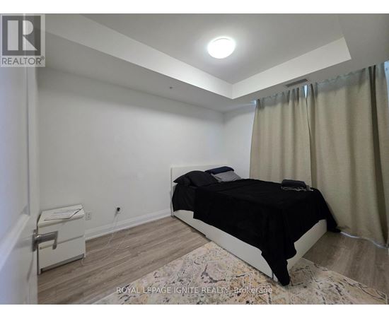 A bedroom with a bed, nightstand, and window with curtains.