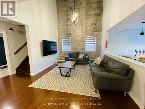 A living room with a black couch and a rug.