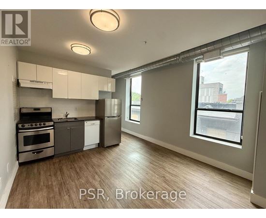 A well-lit kitchen with stainless steel appliances and wooden flooring.