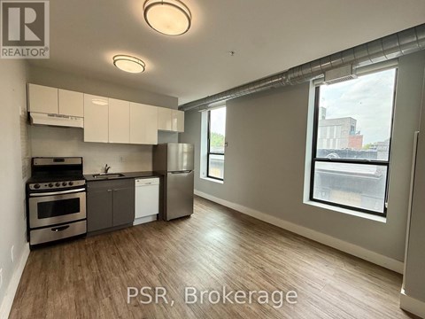 A well-lit kitchen with stainless steel appliances and wooden flooring.