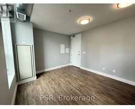 A room with wood flooring and a door on the left side.