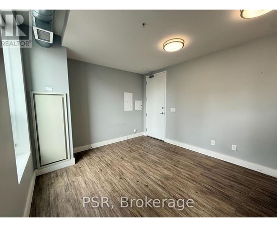 A room with wood flooring and a door on the left side.