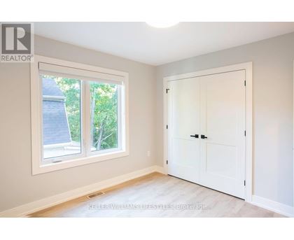 A room with a white door and a window showing a view of a house and trees.