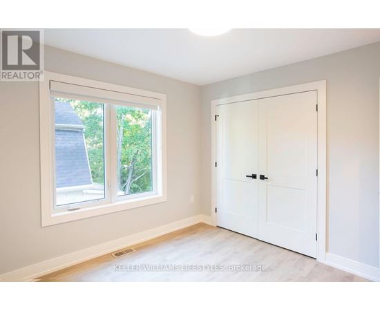 A room with a white door and a window showing a view of a house and trees.