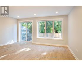 A spacious room with a large window and wooden flooring.