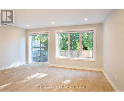 A spacious room with a large window and wooden flooring.