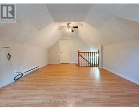 A spacious room with wooden floors and a ceiling fan.