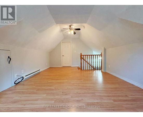 A spacious room with wooden floors and a ceiling fan.