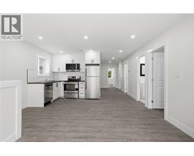A spacious kitchen with white cabinets and a grey floor.