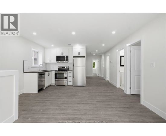 A spacious kitchen with white cabinets and a grey floor.