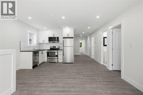 A spacious kitchen with white cabinets and a grey floor.