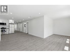 A spacious, empty room with wooden flooring and white walls.