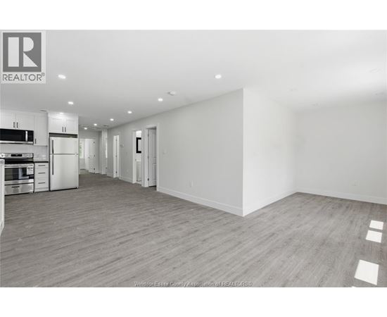 A spacious, empty room with wooden flooring and white walls.