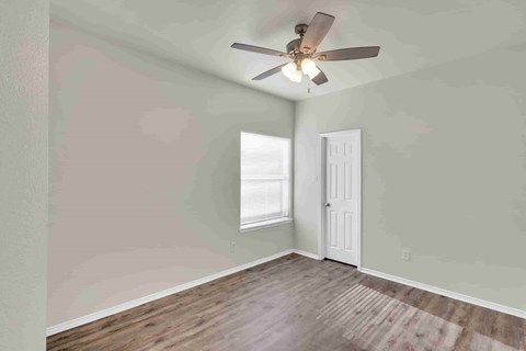 A room with a ceiling fan and a door.