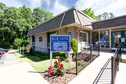 A building with a sign that says "ELEVATE" and "AT THE ROOF LEASING OFFICE" with a phone number.