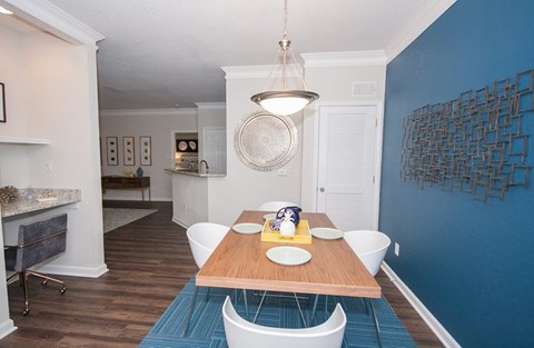 A dining room with a wooden table and white chairs.