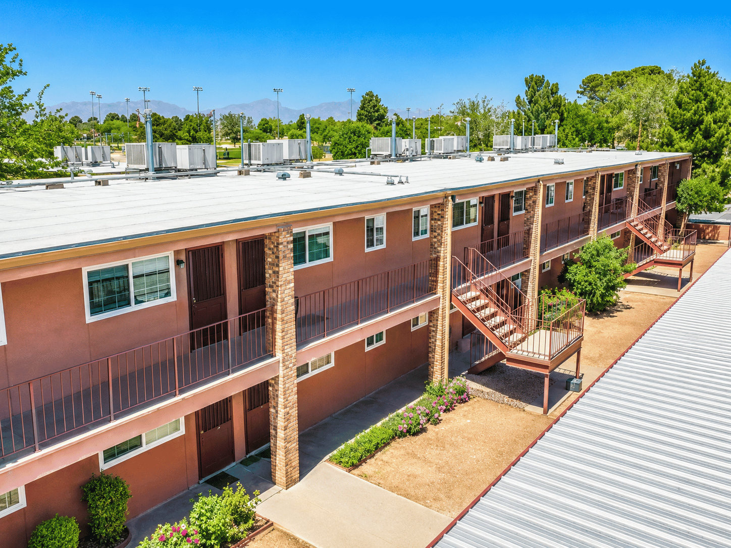 A view of a courtyard with a metal roof and a building with red walls and balconies.