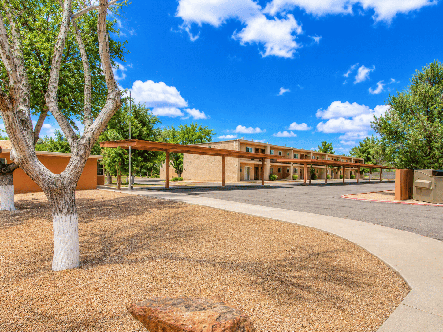 A building with a brown roof and a tree in front of it.