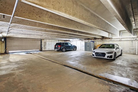 Two cars are parked in a large, empty garage.