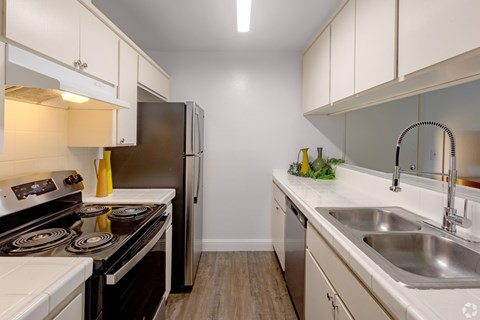 A kitchen with a stove, refrigerator, and sink.