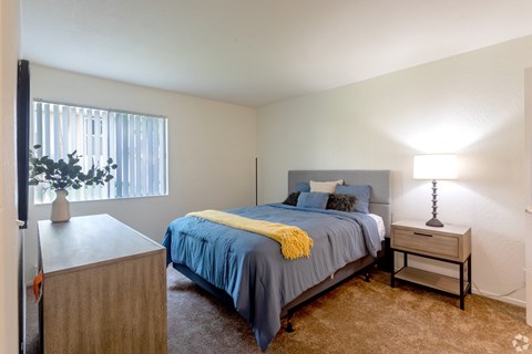 A bedroom with a bed, nightstand, and lamp.