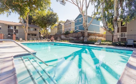 A swimming pool surrounded by trees and buildings.