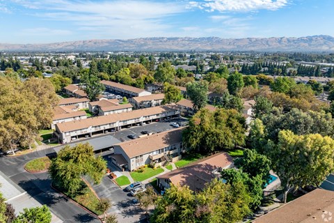 A large building surrounded by trees with mountains in the background.