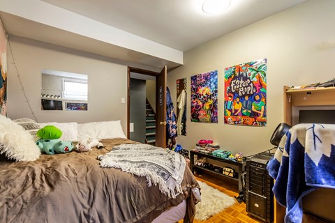 A bedroom with a bed, a desk, and a painting on the wall.