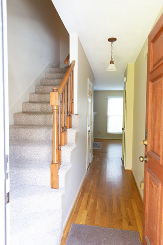 A hallway with a staircase and a light hanging from the ceiling.