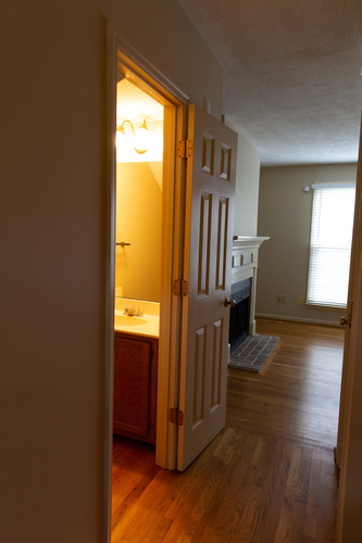 A bathroom with a sink and a toilet is visible through an open door.