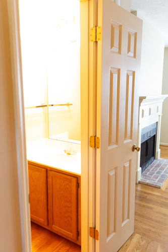 A white door with a gold handle is open.