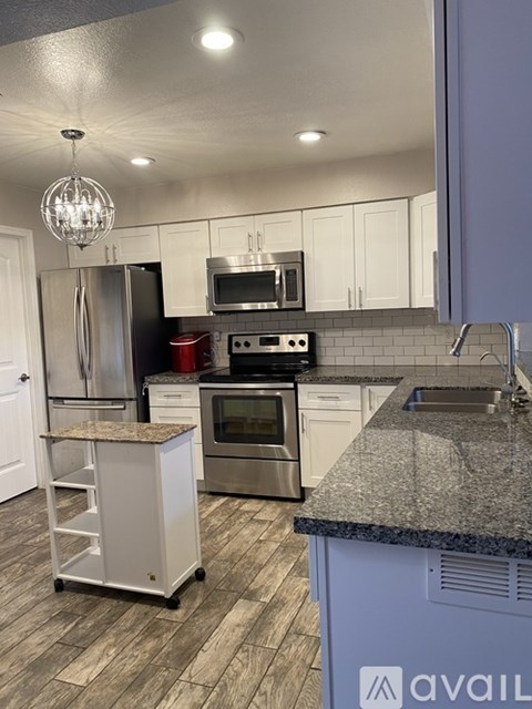 A kitchen with a granite counter top and a chandelier hanging from the ceiling.