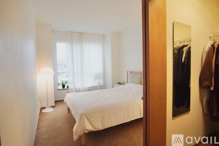 A bedroom with a bed, a lamp, and a mirror.