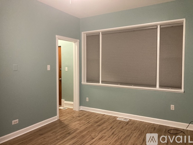 A room with a wooden floor and a window with blinds.