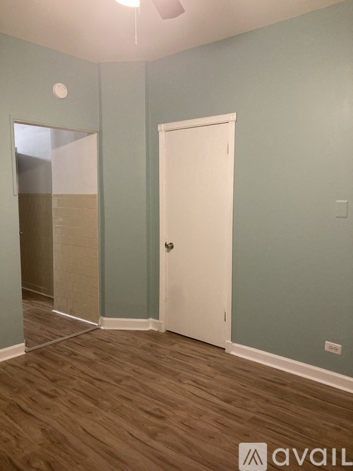 A room with a white door and wooden flooring.