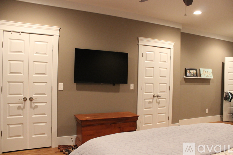 A bedroom with a bed, a television, and two doors.