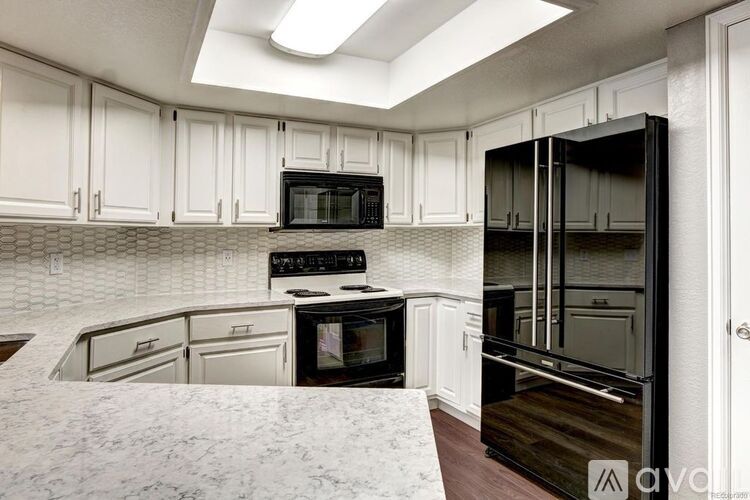 A kitchen with white cabinets and a black refrigerator.