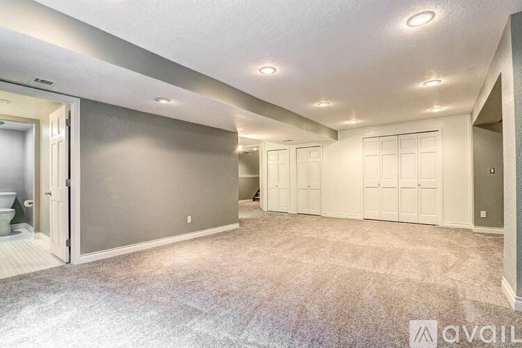 A spacious room with a carpeted floor and a doorway leading to another room.