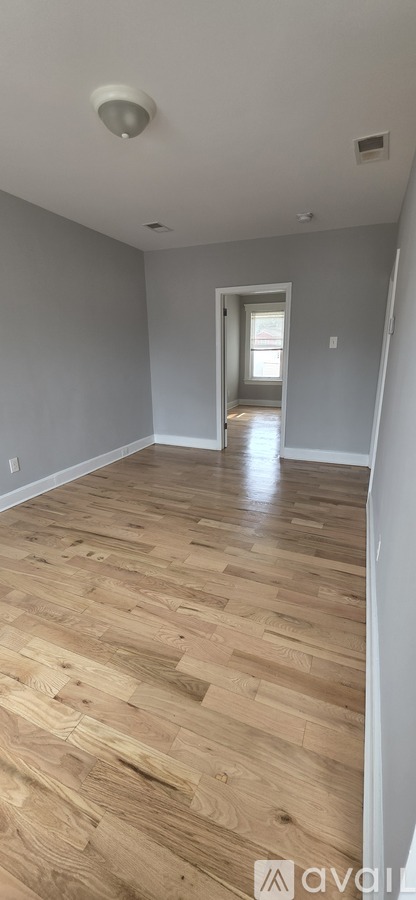 A room with wooden flooring and a doorway leading to another room.