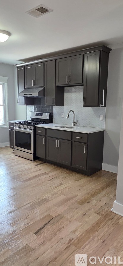 A kitchen with black cabinets and a wooden floor.