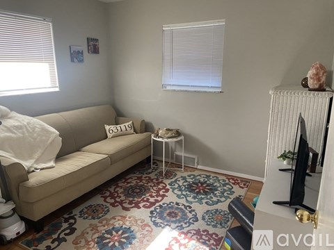 A living room with a beige couch and a colorful rug.