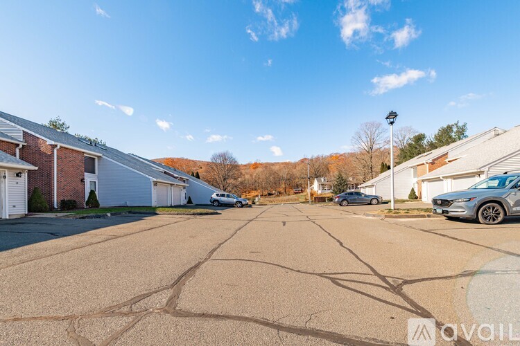 A parking lot with a few cars and houses in the background.