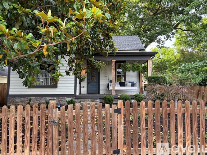 A house with a grey roof and a wooden fence in front.
