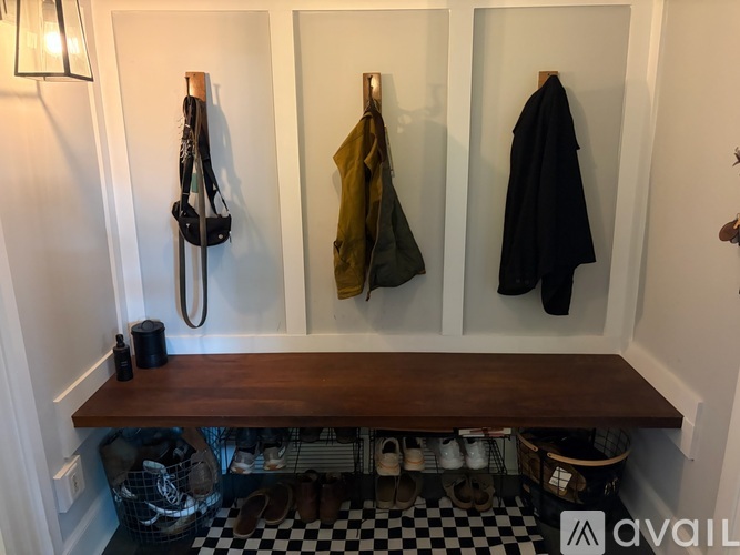 A hallway with a bench, coat rack and shoes.
