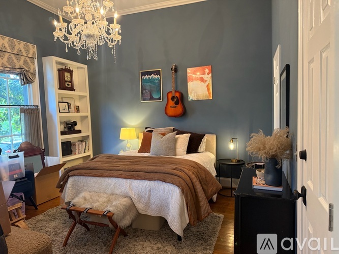 A bedroom with a large bed, a guitar on the wall, and a chandelier.